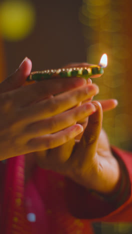 Vertical-Video-Close-Up-Of-Man-Handing-Lit-Diya-Oil-Lamp-To-Woman-Celebrating-Festival-Of-Diwali